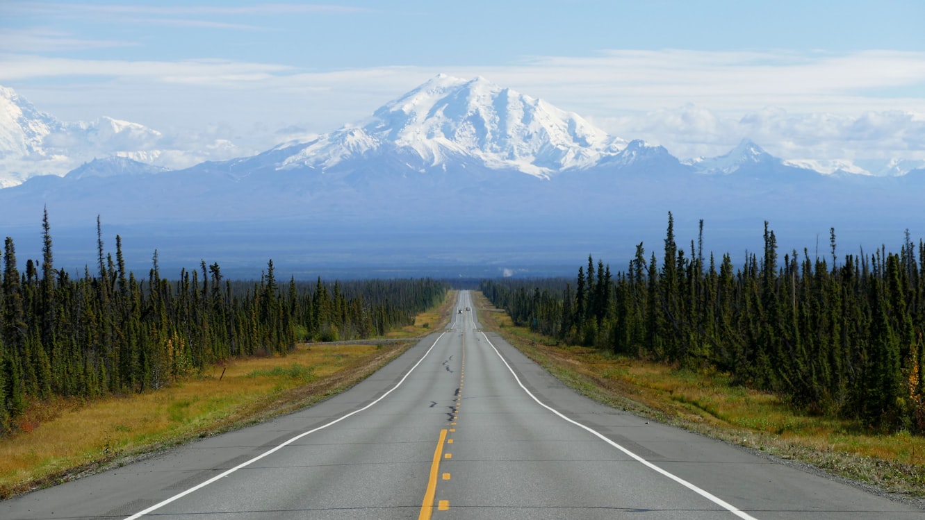 Alaska road leading toward snow mountains